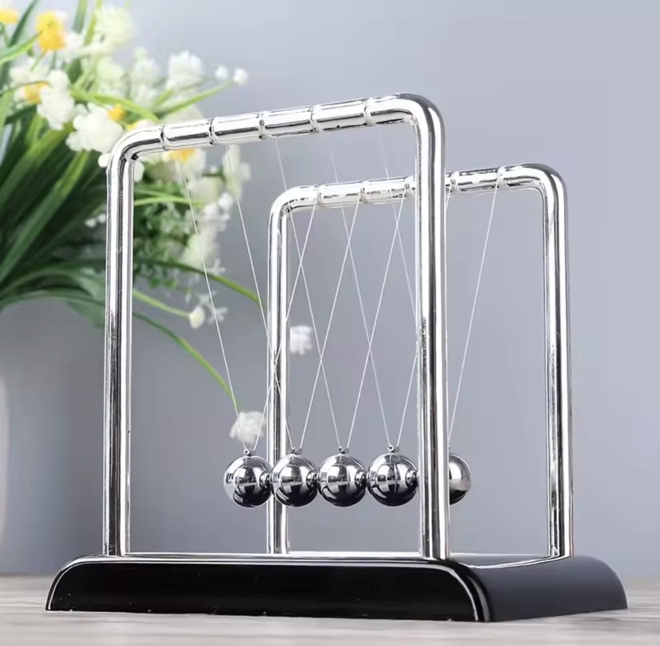 Pendule de Newton en métal chromé posé près d'un bouquet de fleurs