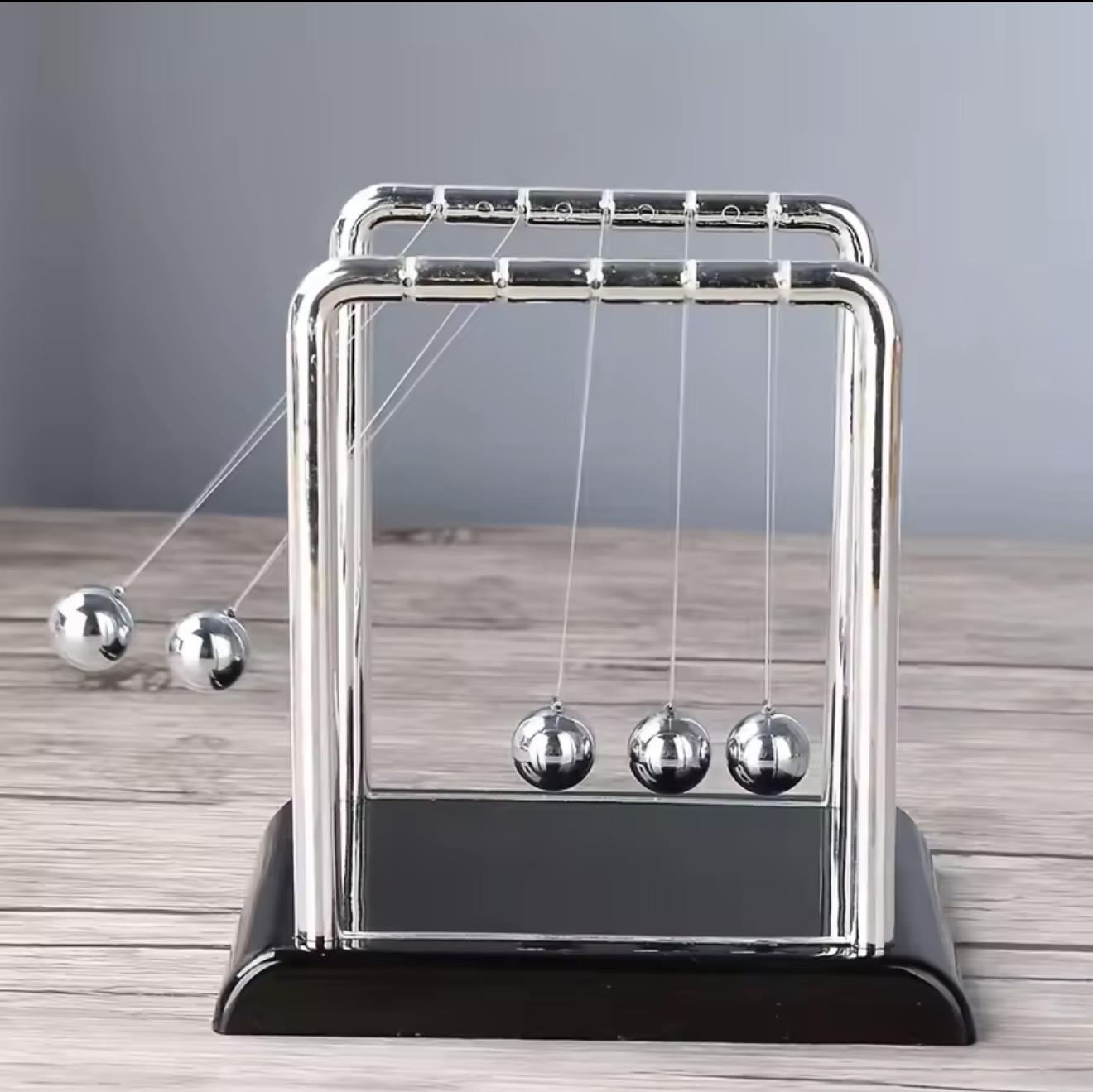 Pendule de Newton en métal chromé en mouvement sur une table en bois